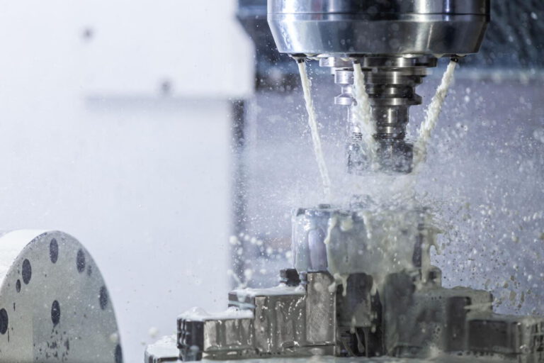CNC-Fräsmaschine bearbeitet ein Metallteil mit Kühlmittel